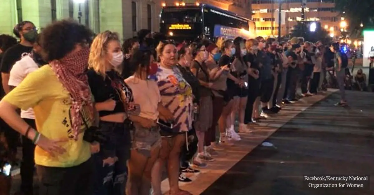 White women form an arm-in-arm shield to protect black protesters at the Louisville Metro Police