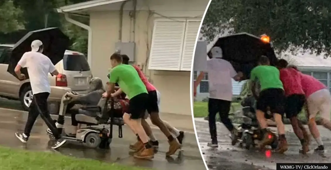 Four men rush to rescue an old lady stuck on her broken scooter in the pouring rain