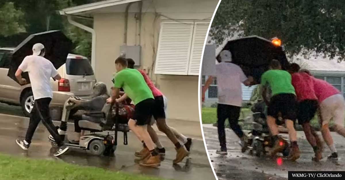 Four men rush to rescue an old lady stuck on her broken scooter in the pouring rain